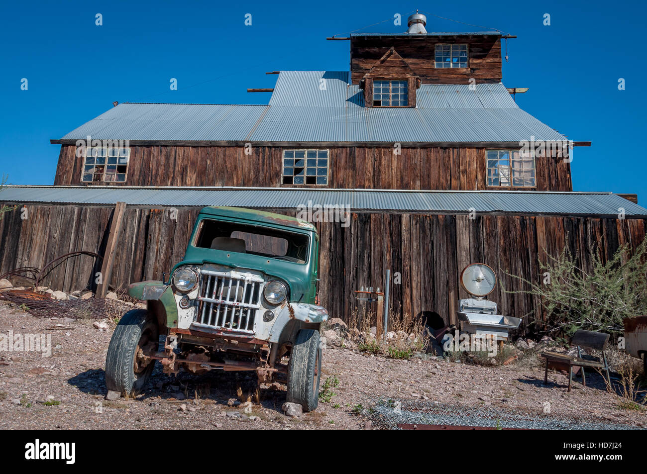 Old green pickup or jeep parked outside abandoned mill in ghost town at Techatticup Mine, Nevada. Stock Photo