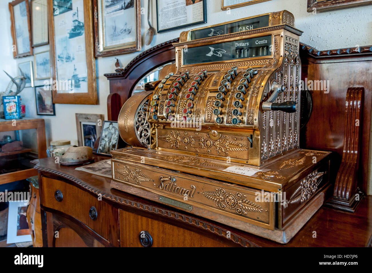 Antique cash register in Gold with National brand across cash drawer and hand crank on side on display on antique wooden bureau Stock Photo