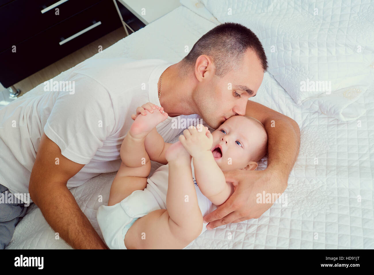 Dad with baby on the bed. Father kissing his little Stock Photo