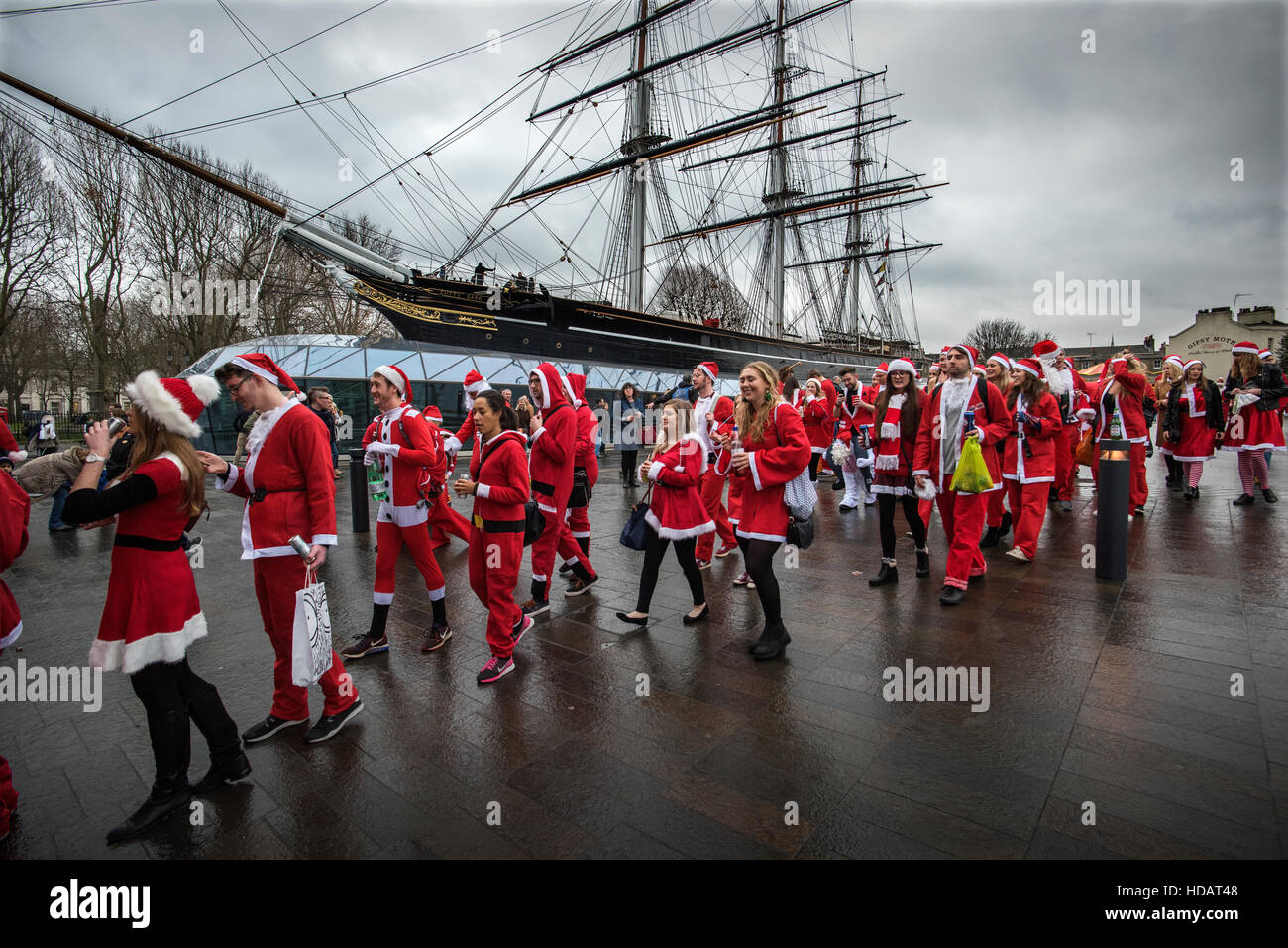 Santacon, Greenwich London England. 10 December 2016 seen here: Passing by the Cutty Sark Tea Clipper at Greenwich London England, hundreds of 'Santa's', men and women of all ages joined in this years Santacon ( Santa Convention) by dressing up as Santa and running and walking from various meeting points in and around London before congrgating for a mass Santacon meet up in Trafalgar Square.....for no other reason other to have some pre Christmas fun lubricated with a 'little' achohol. Credit:  BRIAN HARRIS/Alamy Live News Stock Photo