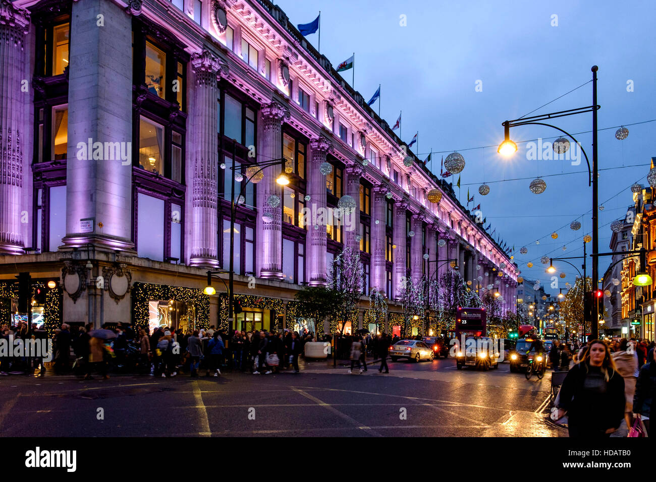 London, UK. 10th Dec, 2016. Christmas Shopping in Londons West End on 10/12/2016 at Oxford Street , . Selfridges is lit in pink, reflecting off of the wet, busy Oxford Street as Shoppers and Traffic passes. Credit:  Julie Edwards/Alamy Live News Stock Photo