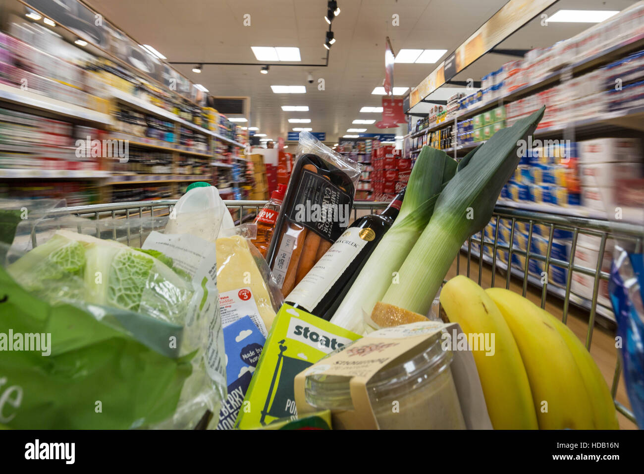 A shopping trolley with groceries is pushed around a supermarket in