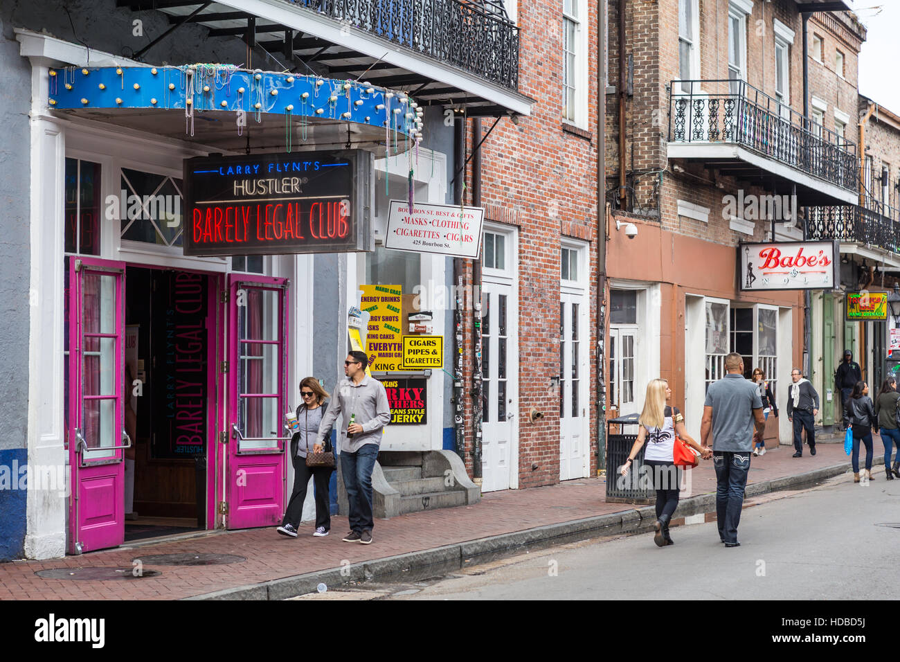 Tourists walk past shops, bars, and gentlemen's clubs on Bourbon Street in the French Quarter of New Orleans, Louisiana. Stock Photo