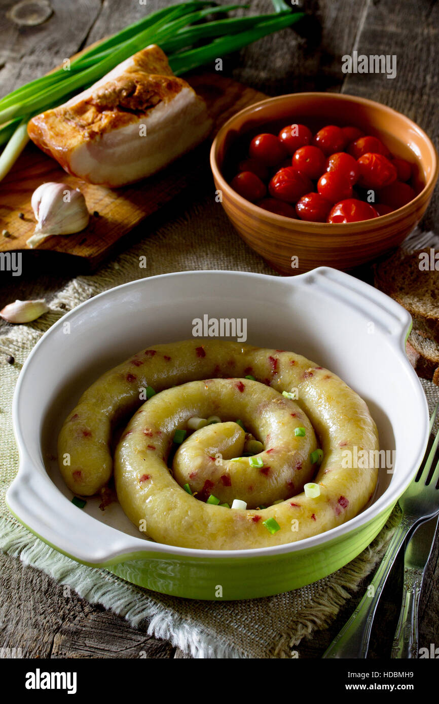 Homemade baked sausage with potatoes and bacon on a rustic background