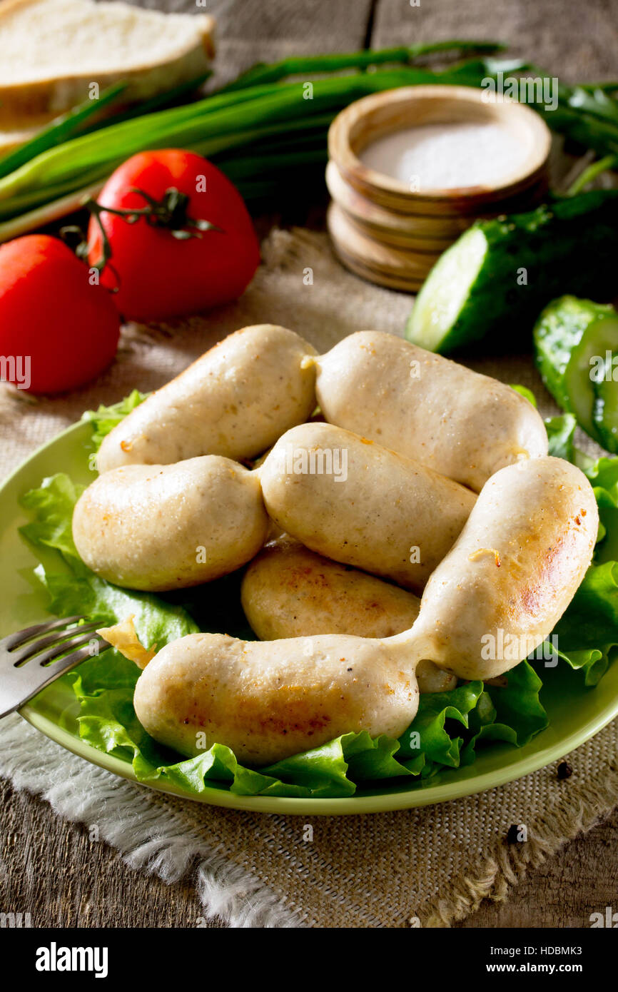 Homemade chicken sausage meat and various vegetables, herbs on rustic background. Stock Photo