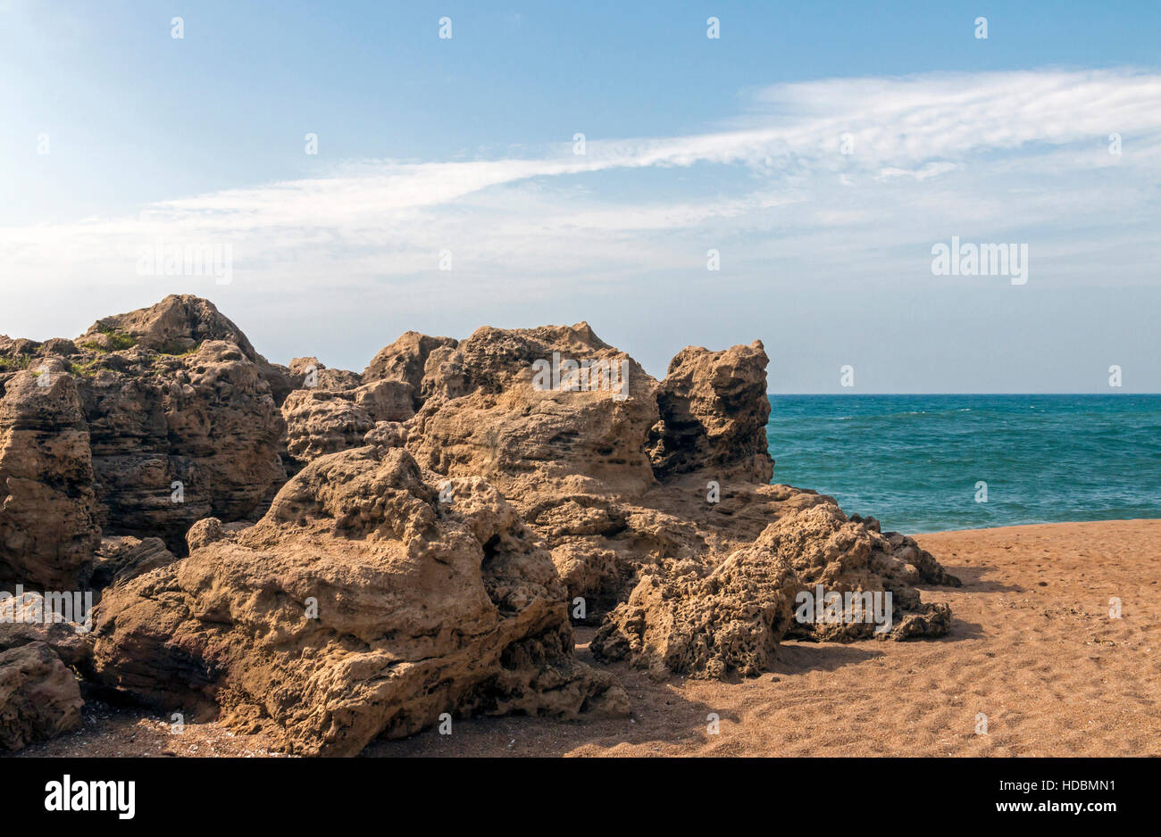 Large formation of rocks on shoreline between beach and ocean against ...