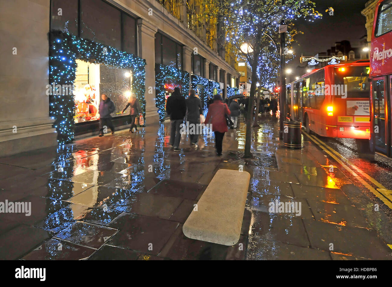 Rainy day in London UK Oxford street with Xmas shoppers and Christmas decorations outside Selfridges West End department store  just stopped raining Stock Photo
