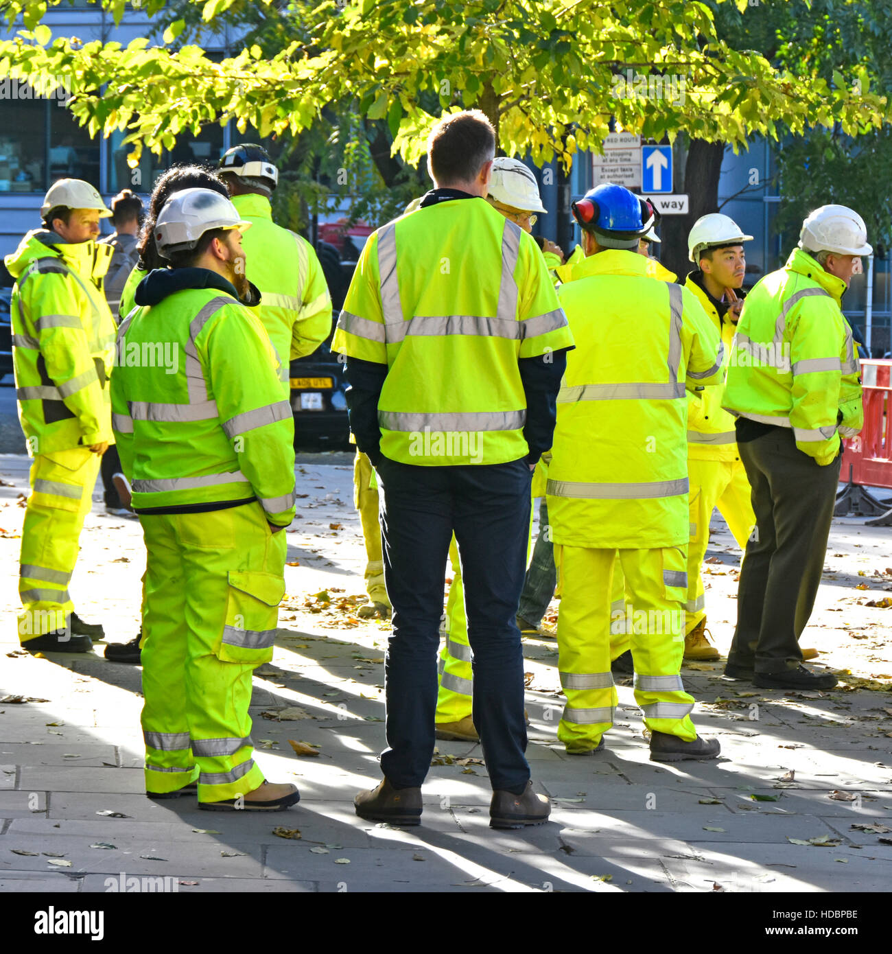 Group of people hard hat men standing around for start of business meeting wearing high visibility clothes major road works project London England UK Stock Photo