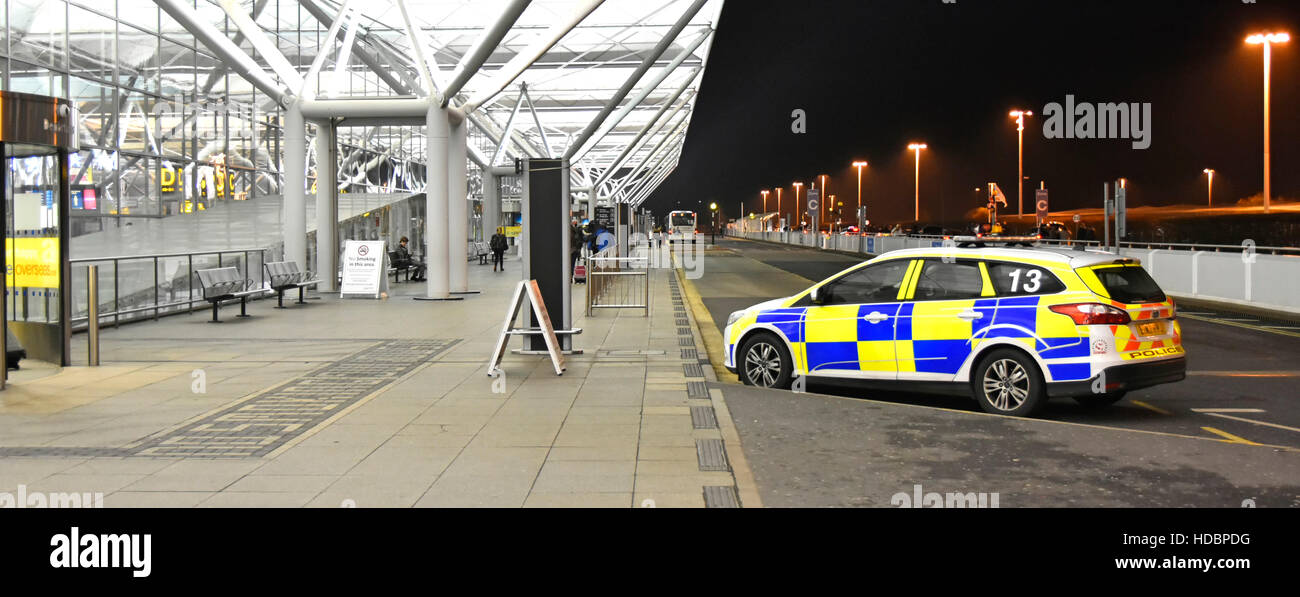 Airport security UK airport terminal building Essex police car and passengers outside front of Stansted Airport cold winter night Stock Photo