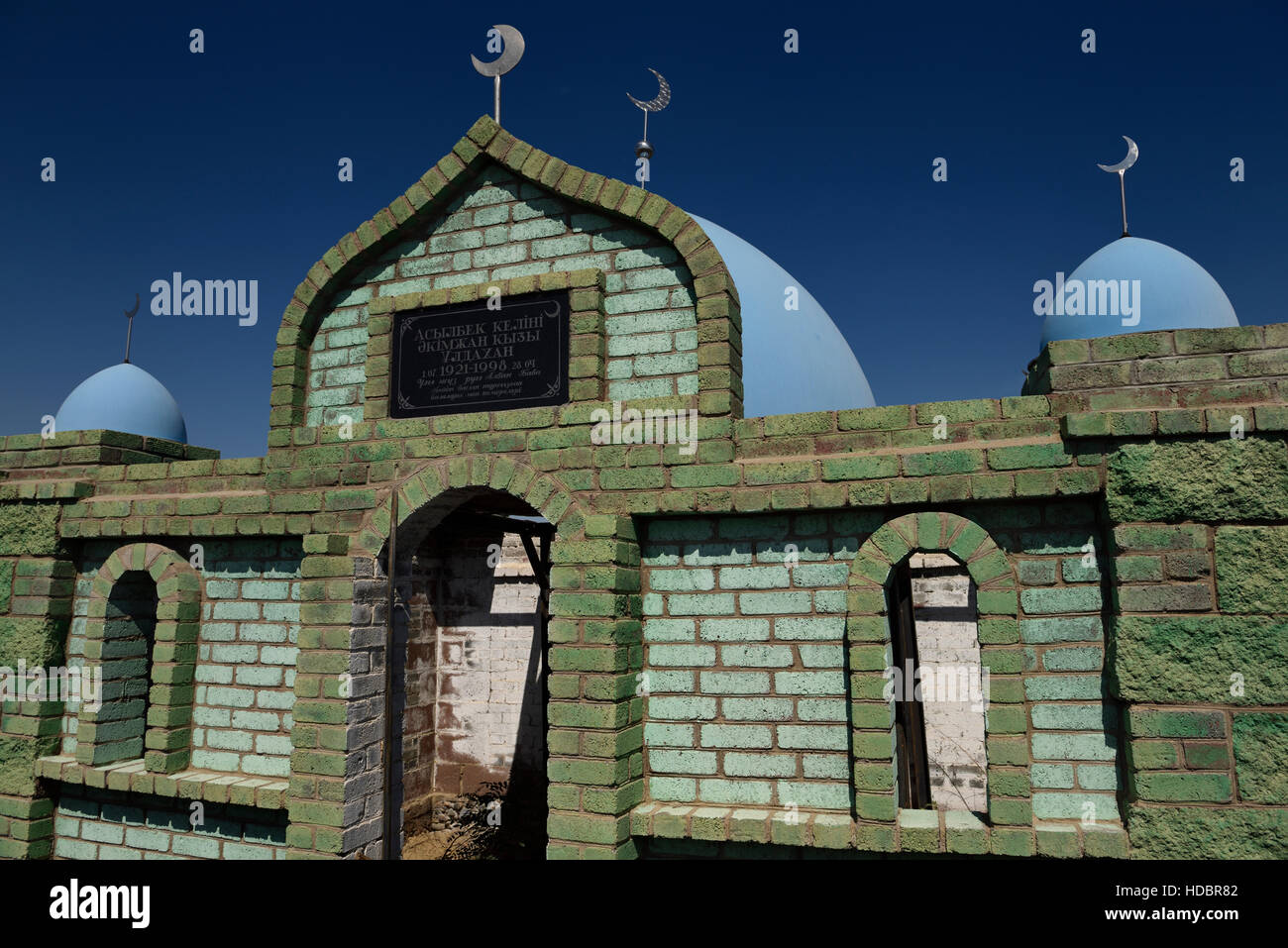 Hilal crescent moon and blue domes on Muslim green brick mausoleums at a cemetery near Shelek Kazakhstan Stock Photo