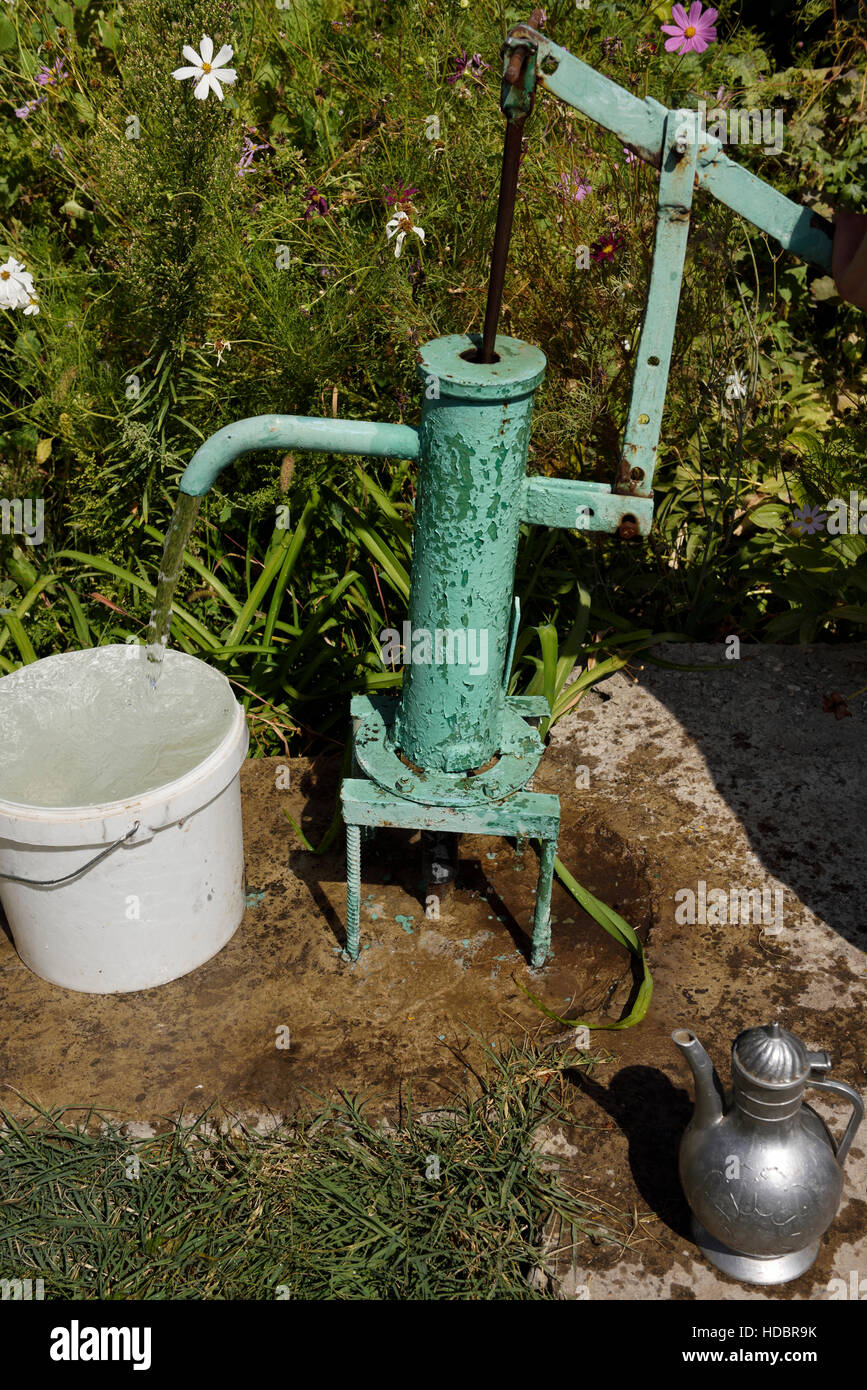 Hand pump with flowing water beside a garden in Shymkent South Kazakhstan Region Stock Photo