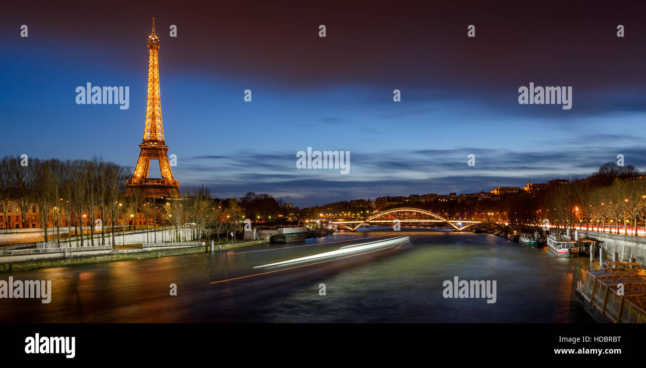 The Eiffel Tower illuminated at twilight with the Seine River banks and the Debilly Footbridge. Paris, France Stock Photo