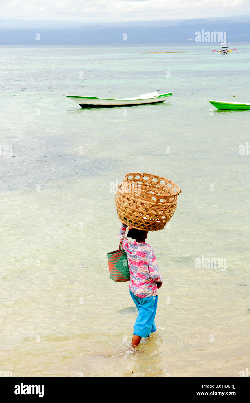 A local woman traverses shallow water in Nusa Lembonagan, Bali, Indonesia, South East Asia Stock Photo
