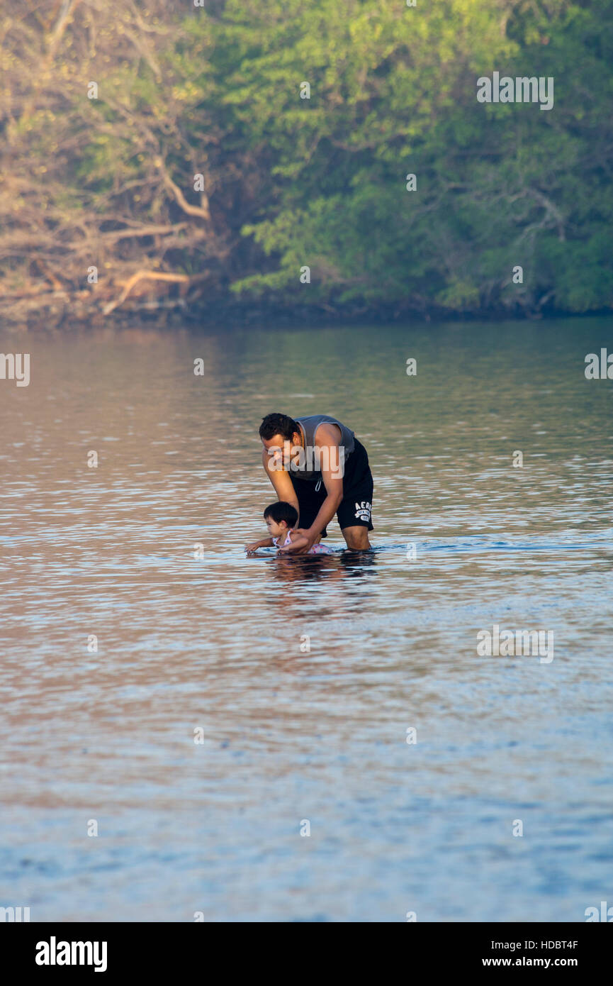 Costa Rican man teaching his daughter to swim on a beach at Papagayo Bay Stock Photo