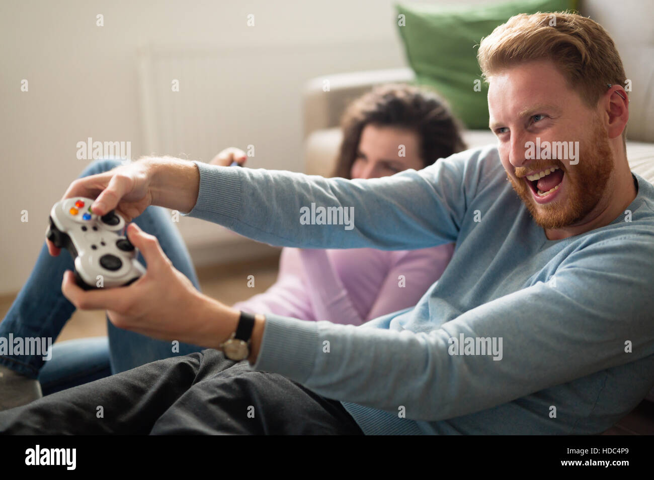 Joyful couple winning video games with joystick on console in