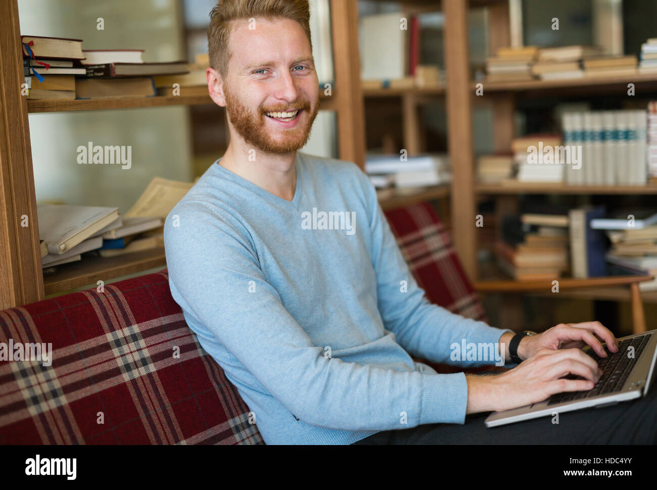 Cheerful student studying for university in library Stock Photo - Alamy