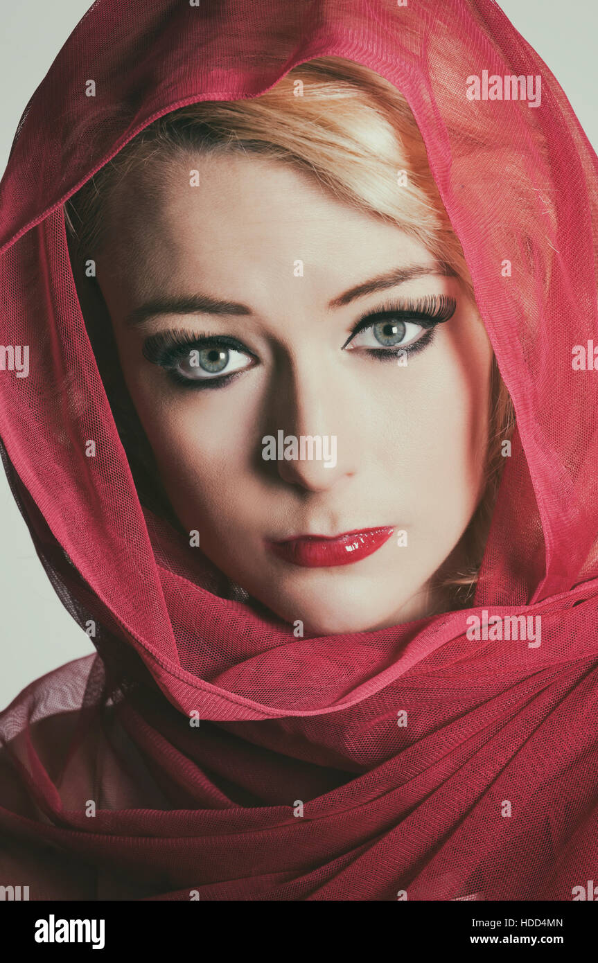 Beautiful woman wearing a red headscarf looking scared Stock Photo
