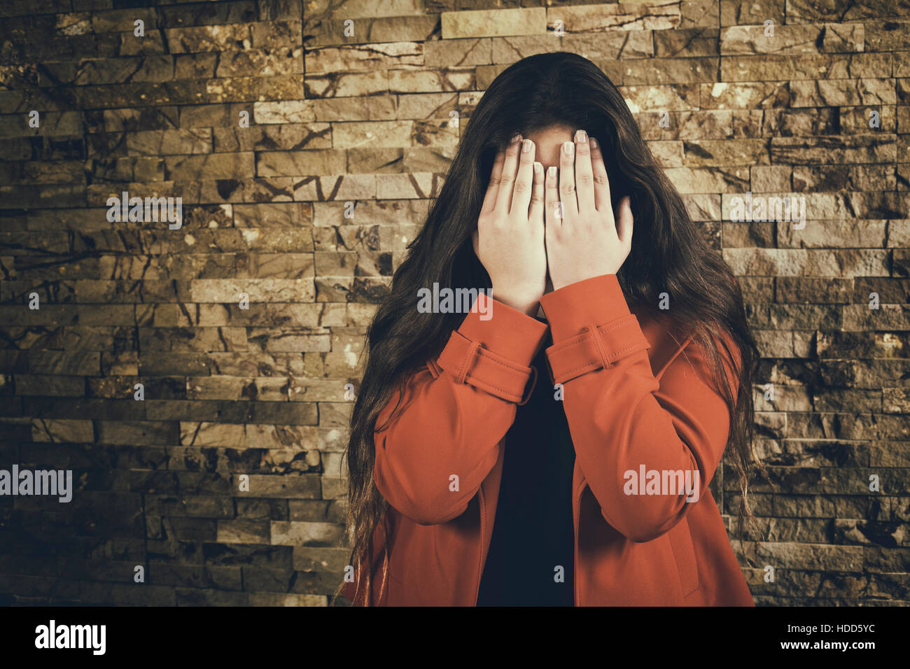Scared teenage girl hiding face with hands crying Stock Photo