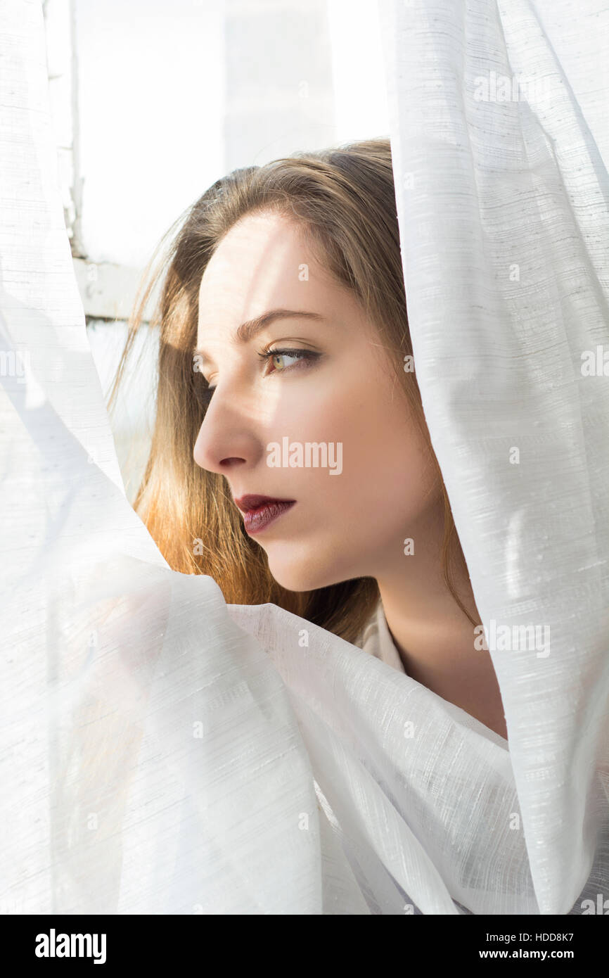 Sad young woman looking out of the window Stock Photo
