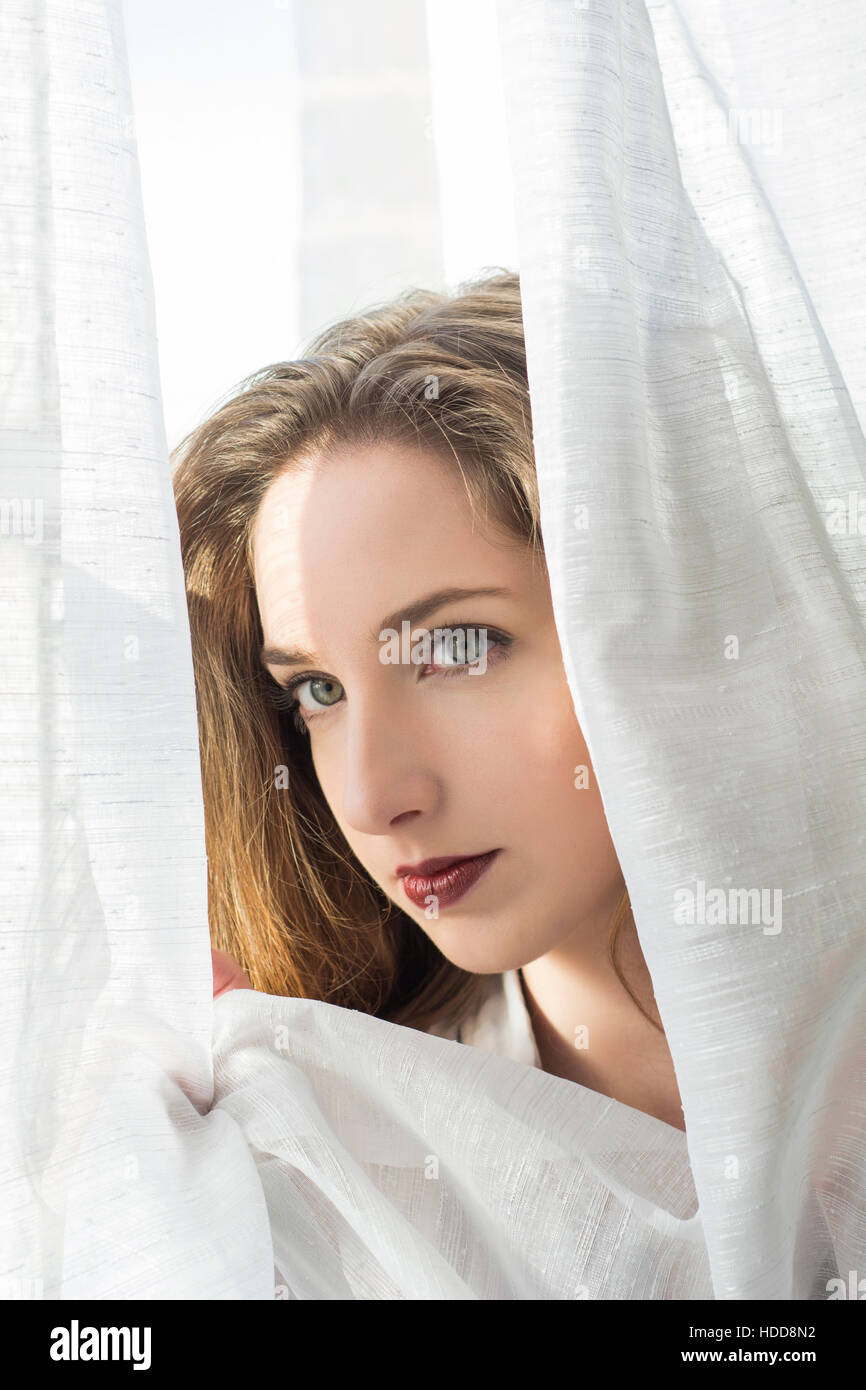 Beautiful young woman looking away by the window Stock Photo