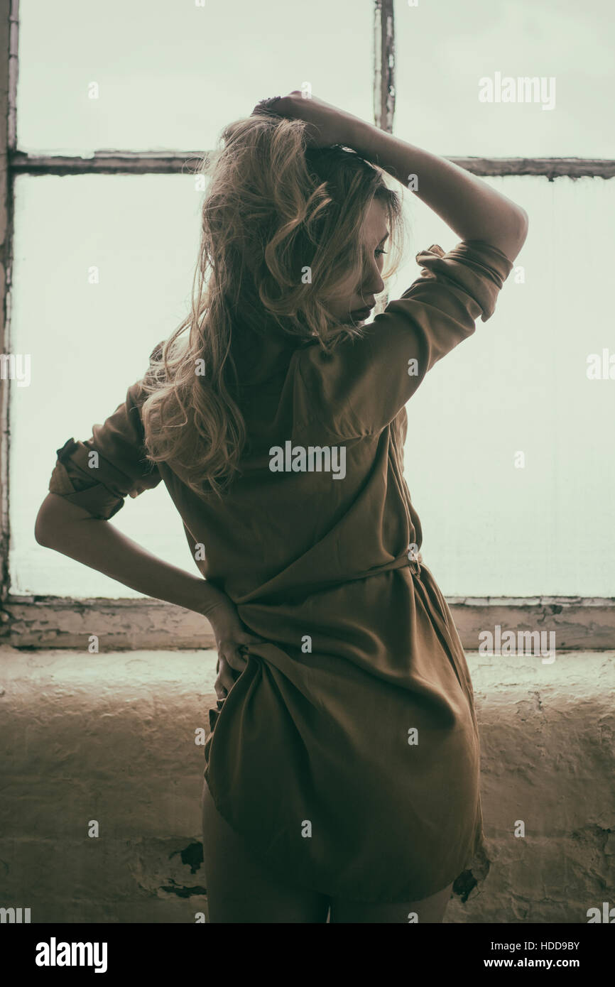 Sad woman standing by the window Stock Photo