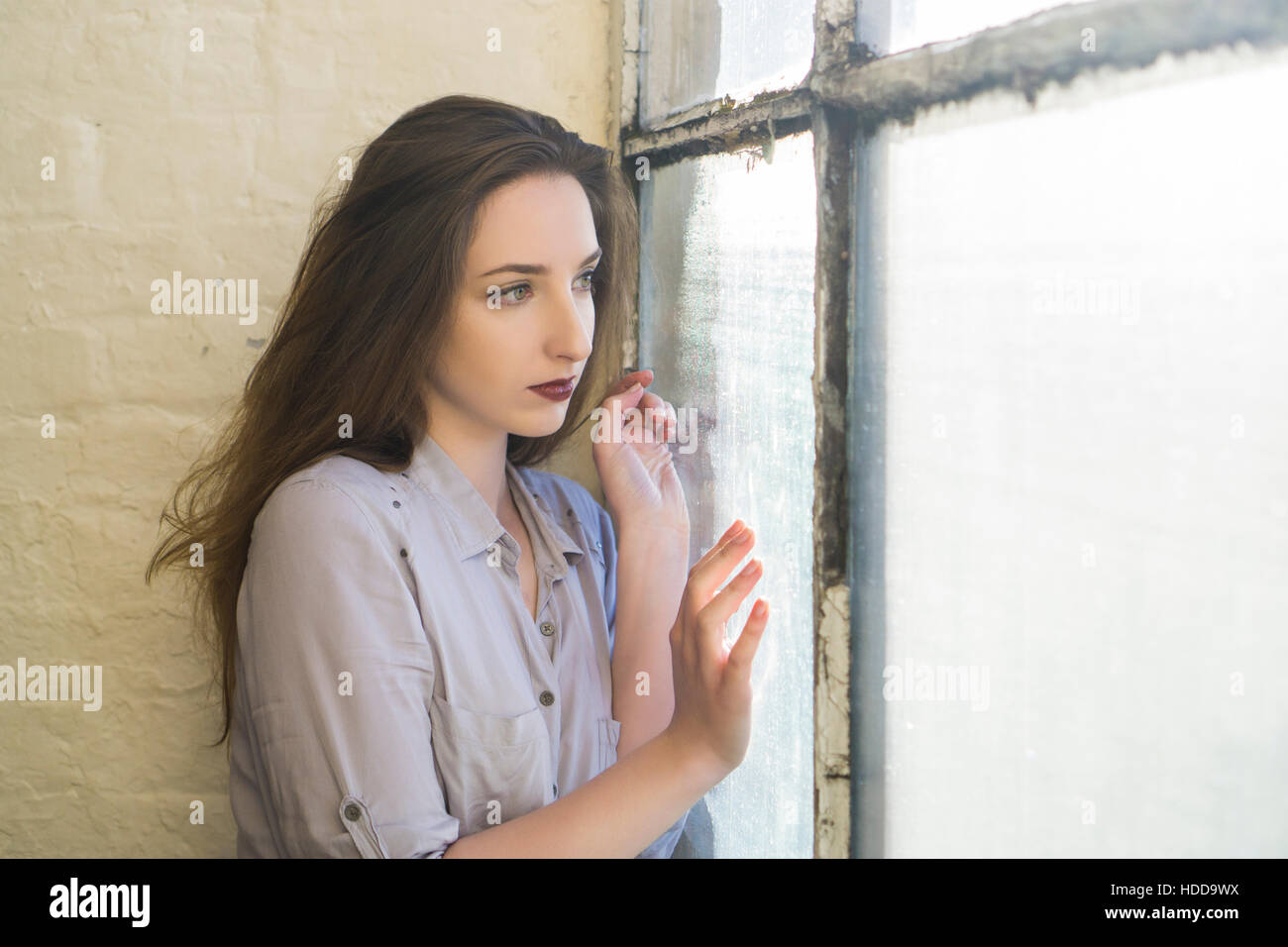 Sad beautiful woman looking out of the window Stock Photo