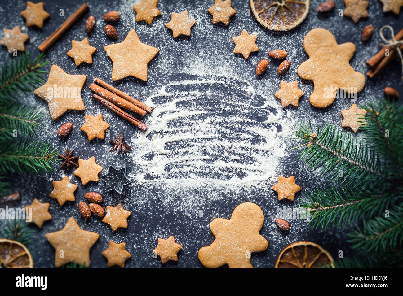 Christmas frame with gingerbread man cookies, gingerbread stars, cinnamon, spices, almonds and fir tree. Copy space for text. Stock Photo