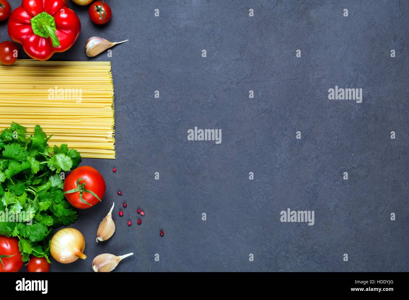 Pasta, spices and vegetables on slate background - cooking ingredients for Italian cuisine. Copy space for text. Top view Stock Photo