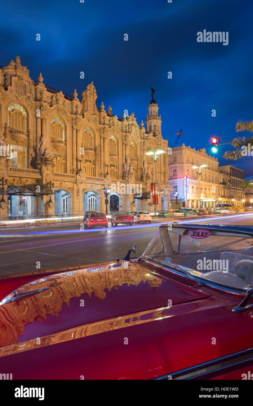 The Gran Teatro de la Habana reflected on 1950's American taxi on Paseo de Marti at night, Havana Stock Photo