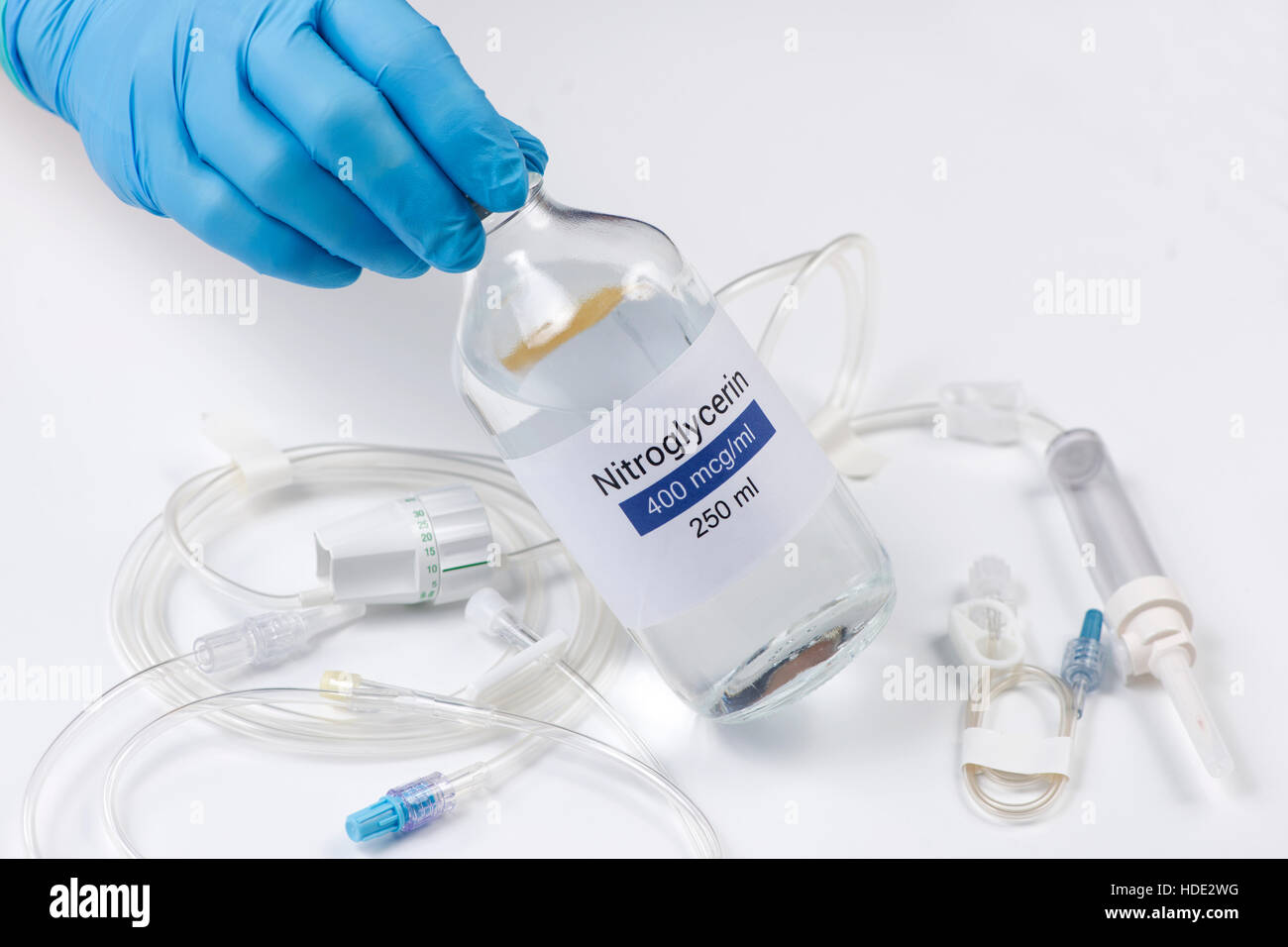 Nitroglycerin bottle held by nurse with iv tubing. Stock Photo
