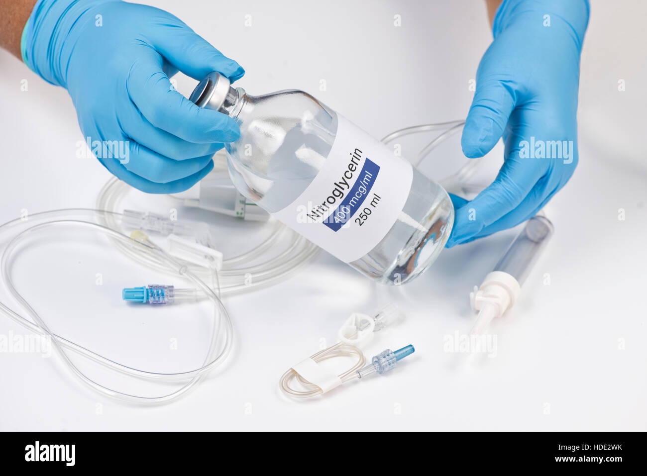 Nitroglycerin bottle held by nurse with iv tubing. Stock Photo