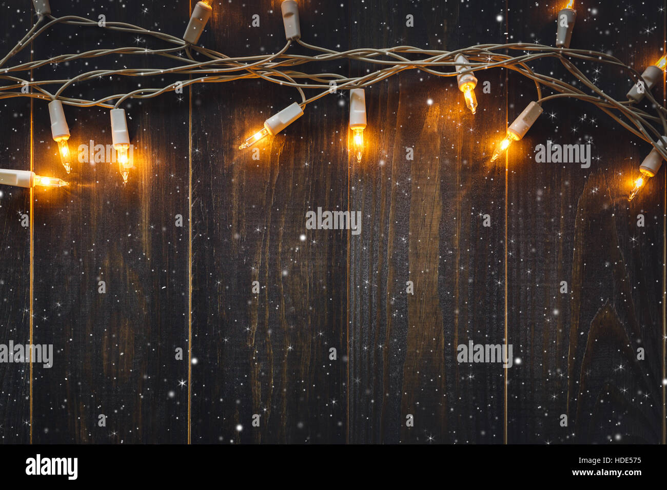 christmas background lights and snow with copy space on old wooden board background Stock Photo
