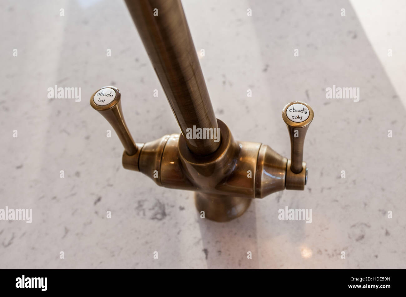 A brass coloured hot and cold mixer tap in a domestic kitchen. Stock Photo