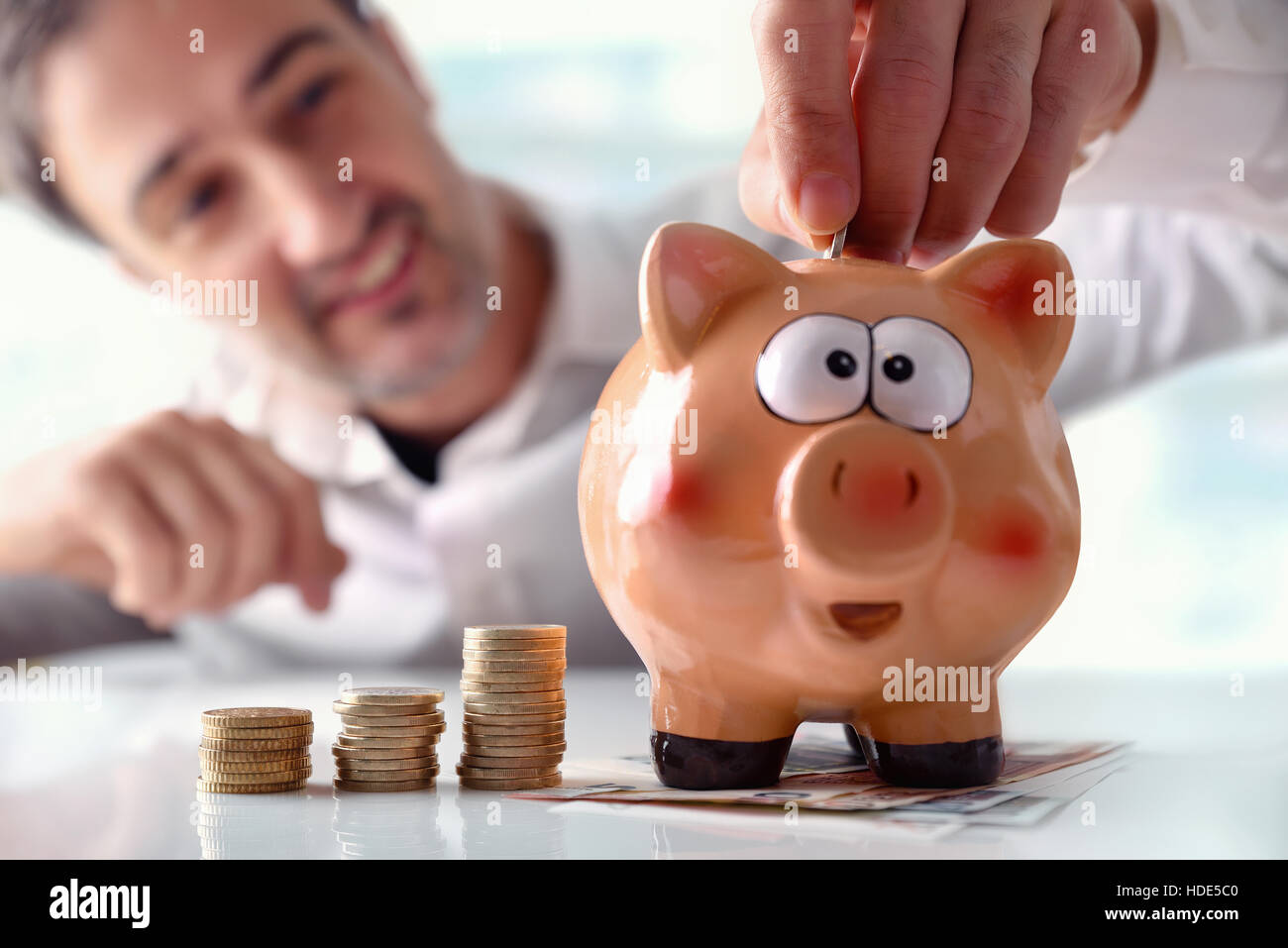 Concept savings with man's hand putting money into piggy bank with ...