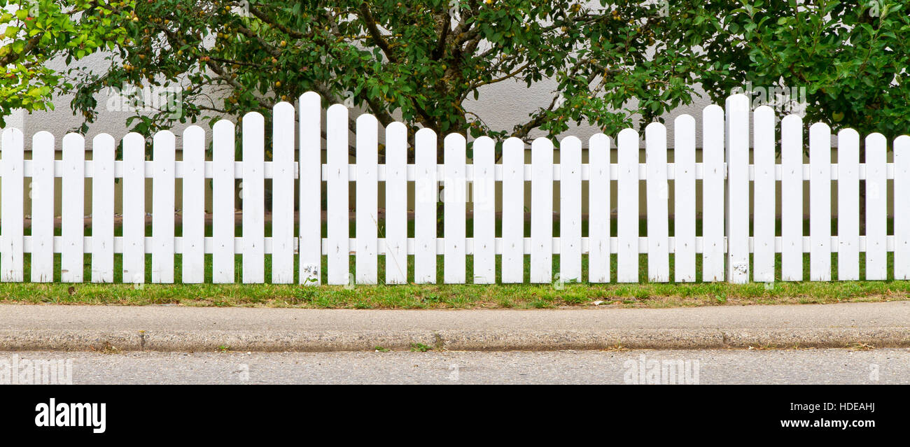 White, wooden fence in front of a garden Stock Photo