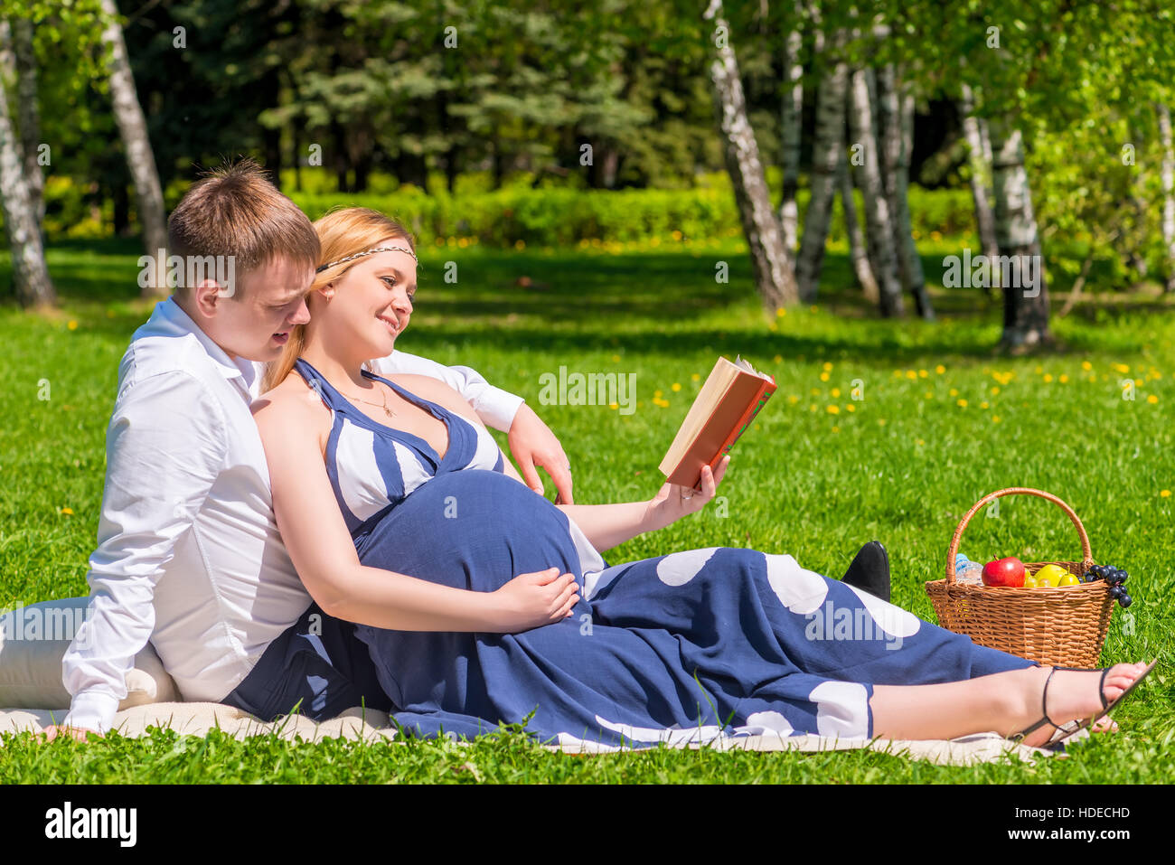 Future young parents reading the book on picnic for children Stock Photo