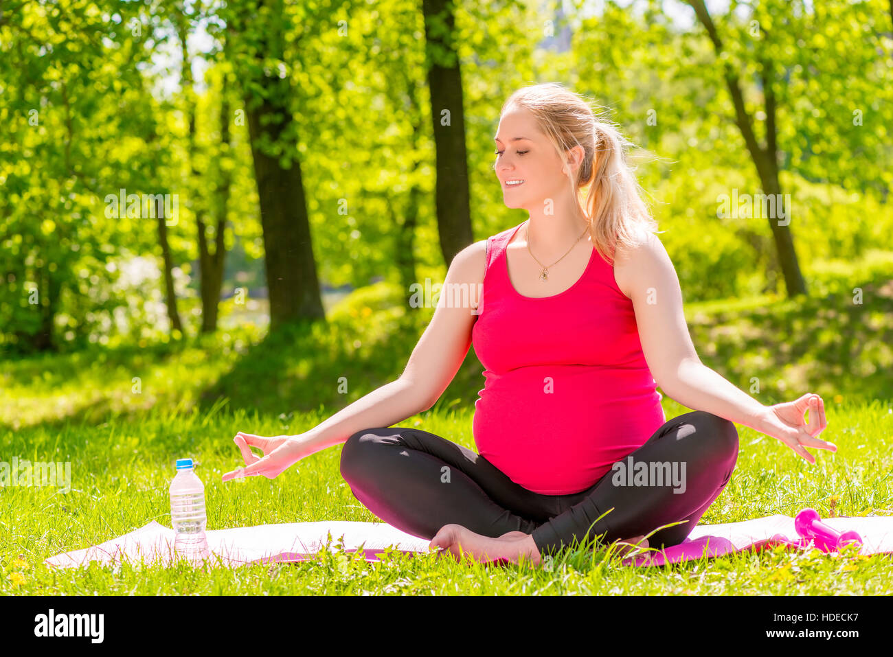 young pregnant woman in a lotus position doing yoga and relaxation Stock Photo