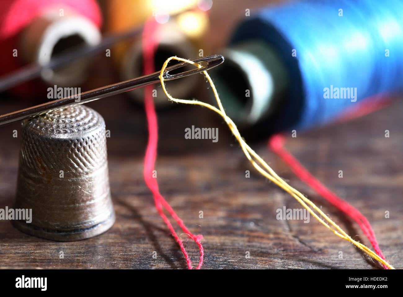 Thimble and needle near thread on old wooden background Stock Photo