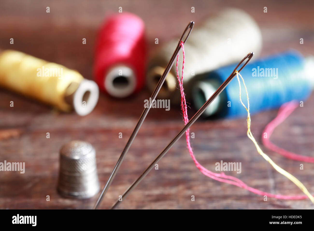Thimble and needles near thread on old wooden background Stock Photo