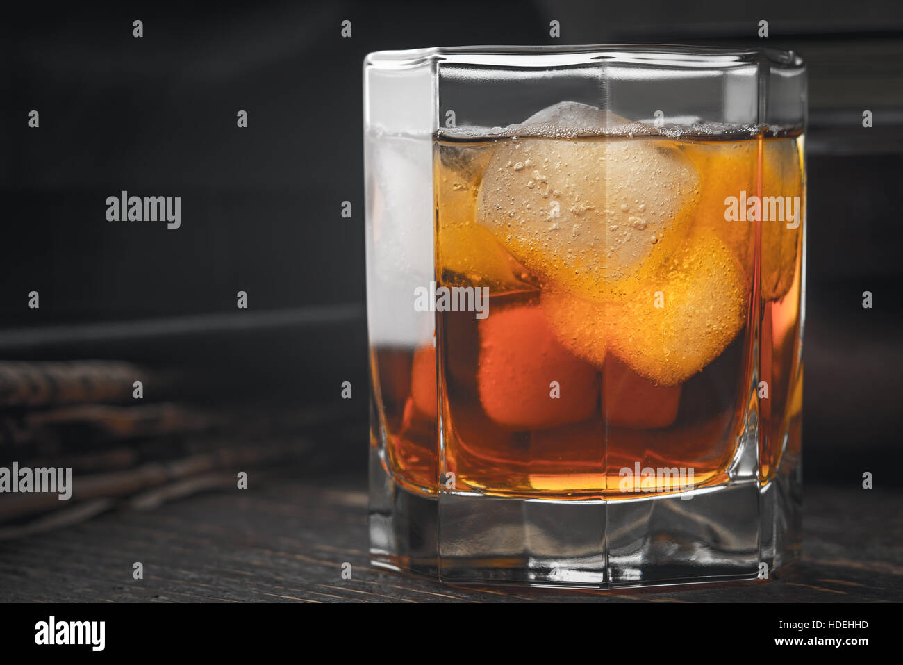 Whiskey with ice  and blurred newspaper on the wooden table Stock Photo