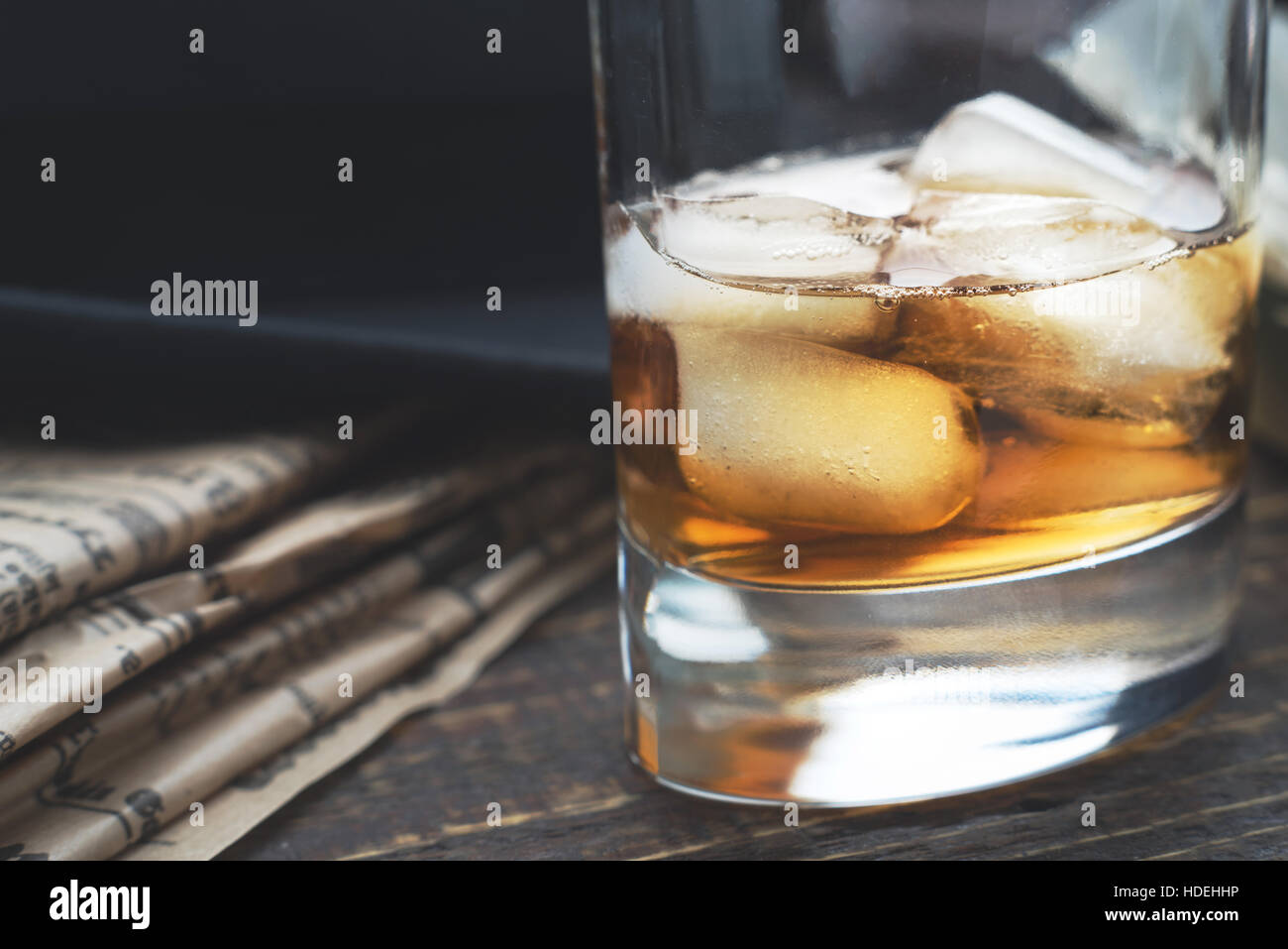 Whiskey with ice  and blurred newspaper on the horizontal Stock Photo
