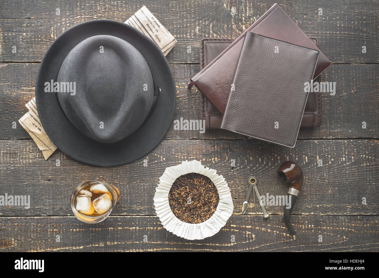 Glass of whiskey , pipe  , hat and newspaper on the wooden table top view Stock Photo