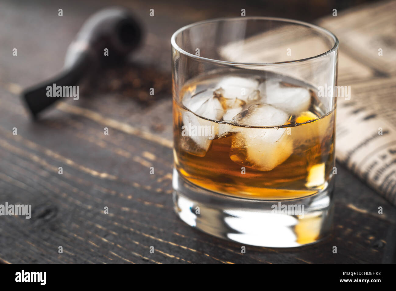 Whiskey with ice  and blurred pipe and newspaper horizontal Stock Photo