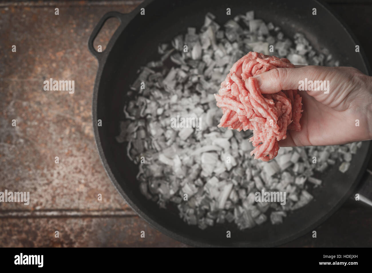 Raw minced meat in the hand with blurred pan top view Stock Photo