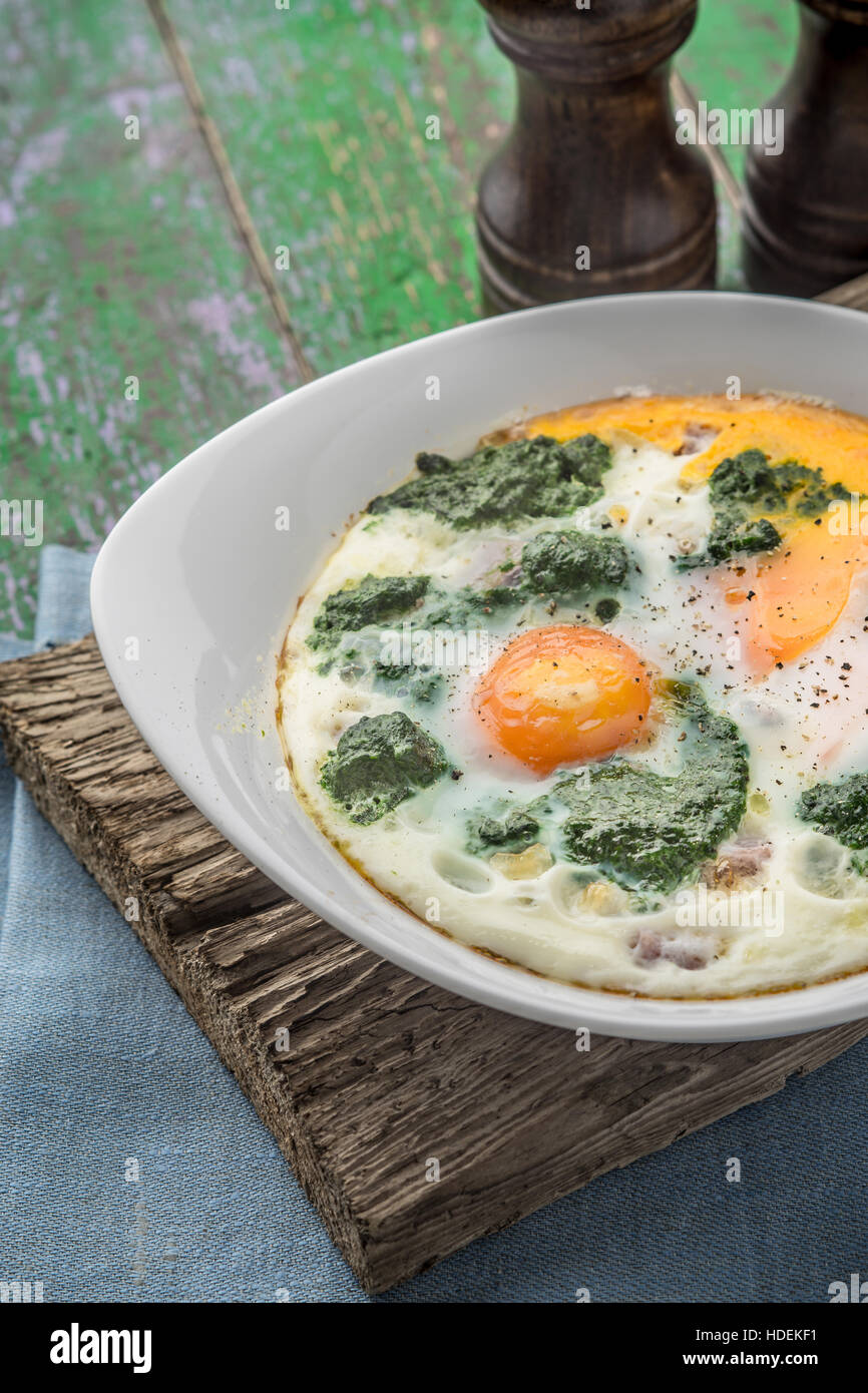 Florentine eggs with pureed spinach on the wooden table vertical Stock Photo