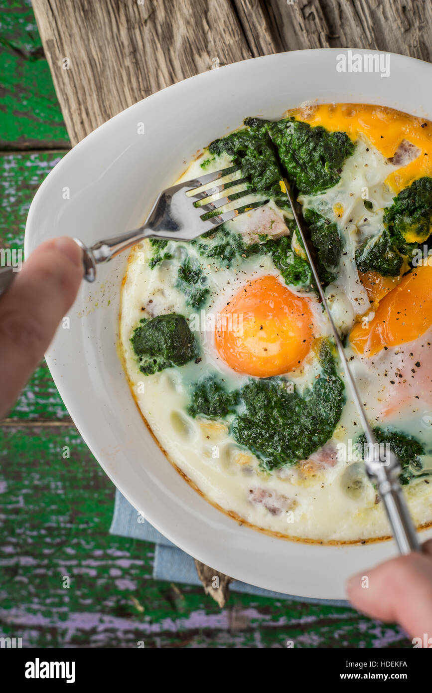 Eating Florentine eggs with purred spinach vertical Stock Photo
