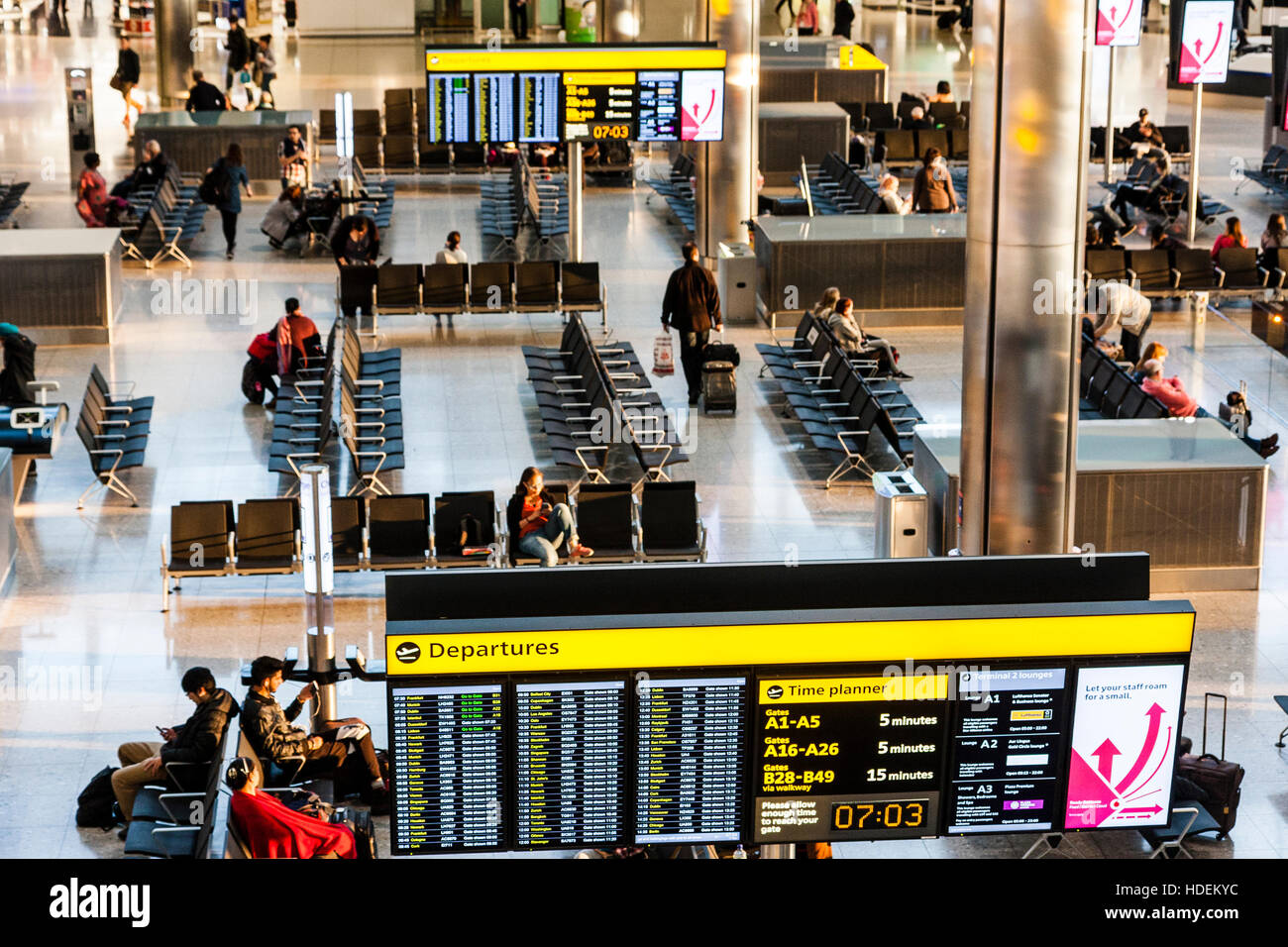 London, Heathrow airport, Terminal 2 interior. Overhead view, information boards for flight departures and times, with seating area. Not busy. Stock Photo