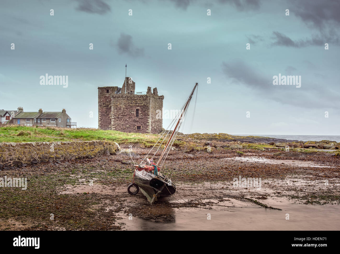 Yacht at low tide with Portencross Castle in the background Stock Photo