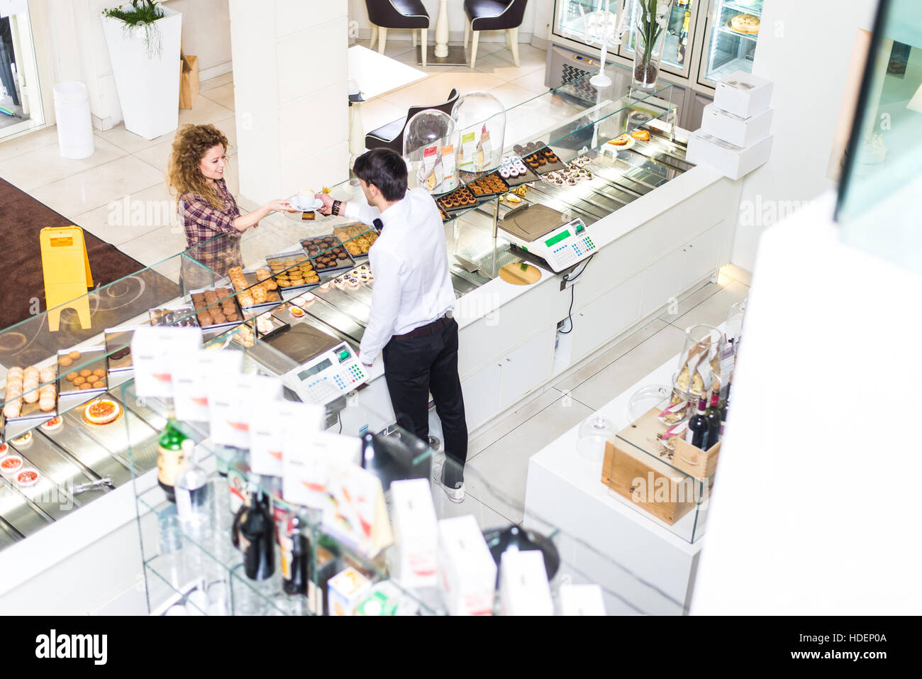 Waiter serving customer in a pastry shop, view from above - Woman buying cake and cookies for breakfast Stock Photo