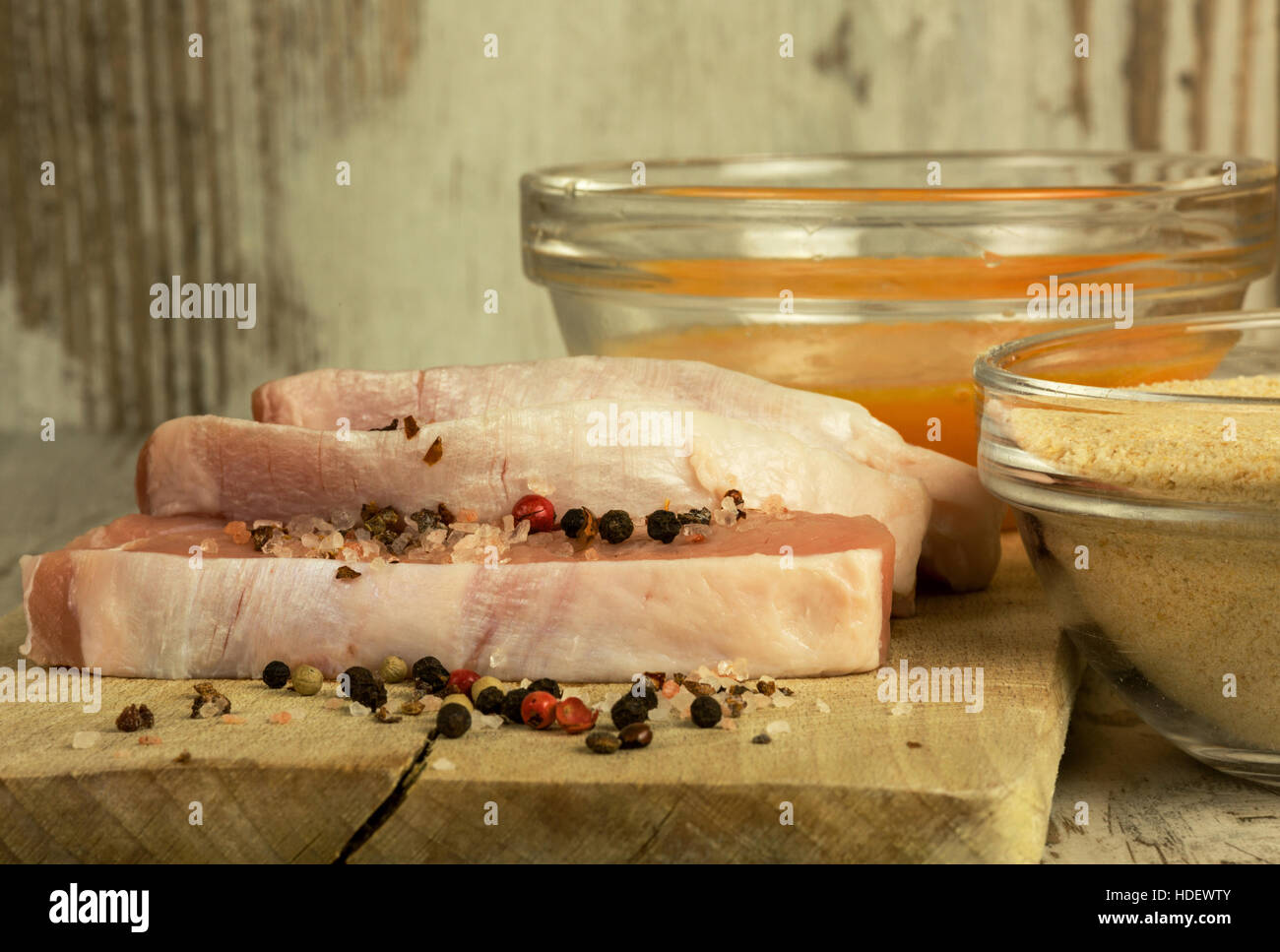 Three pieces of fresh raw pork chops, bowls with bread crumbs and eggs